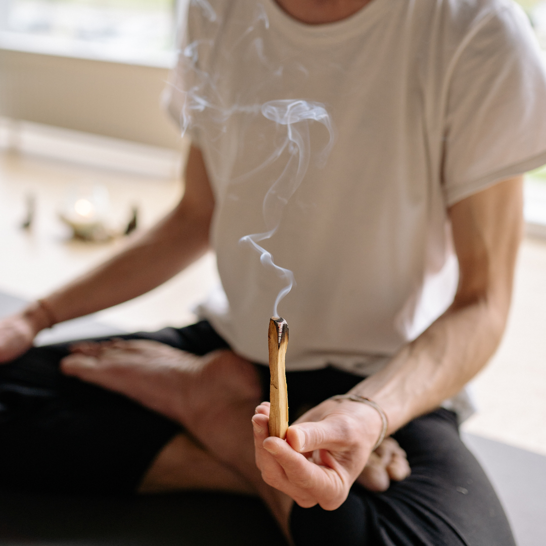 Person burning Palo Santo stick while meditating 