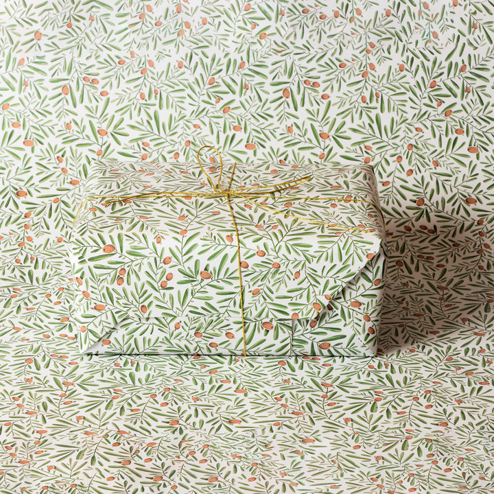 Gift box wrapped in a olive and foliage patterned paper on a matching background.