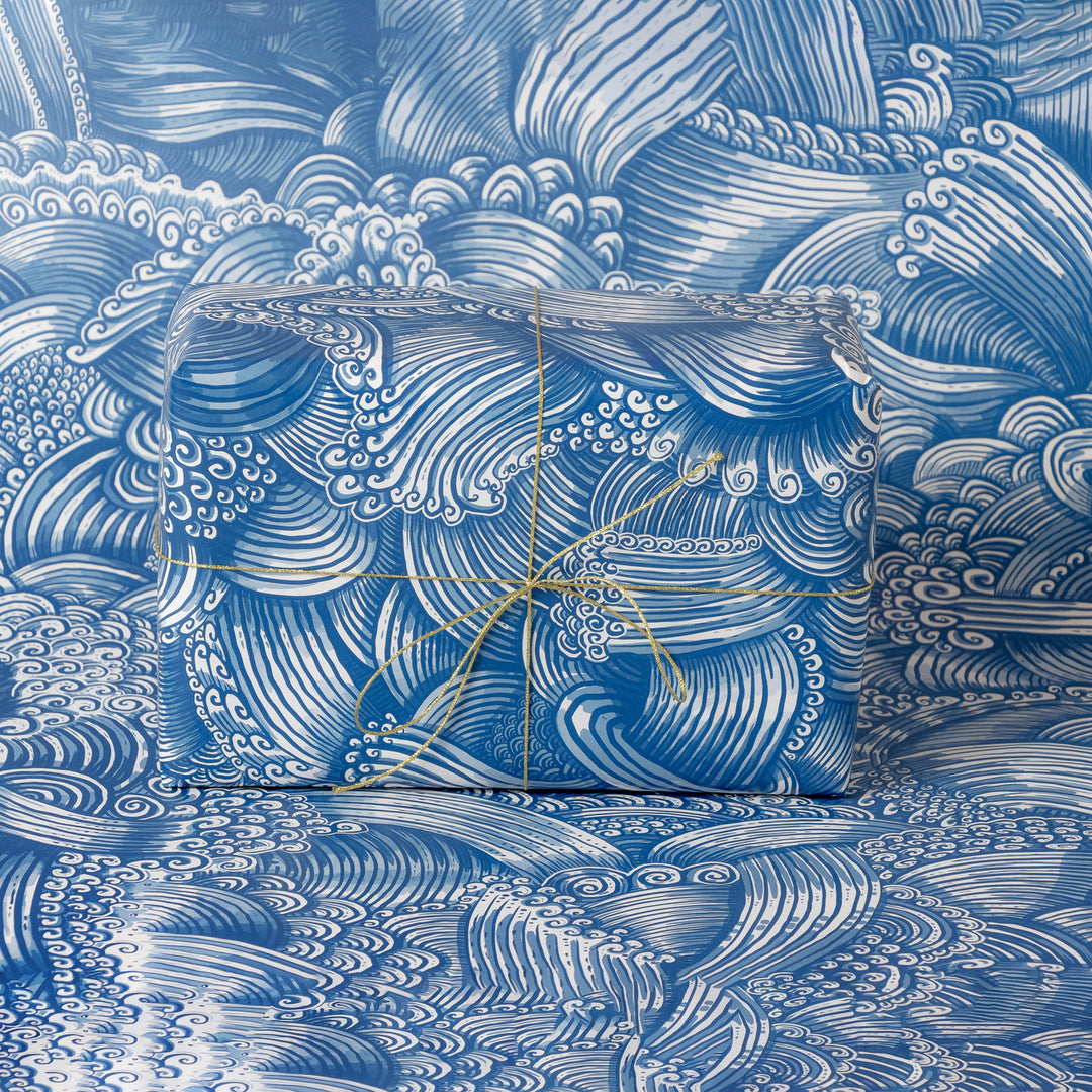Gift box wrapped with blue and white wave-patterned wrapping with matching background