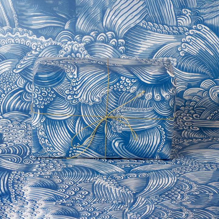 Gift box wrapped with blue and white wave-patterned wrapping with matching background