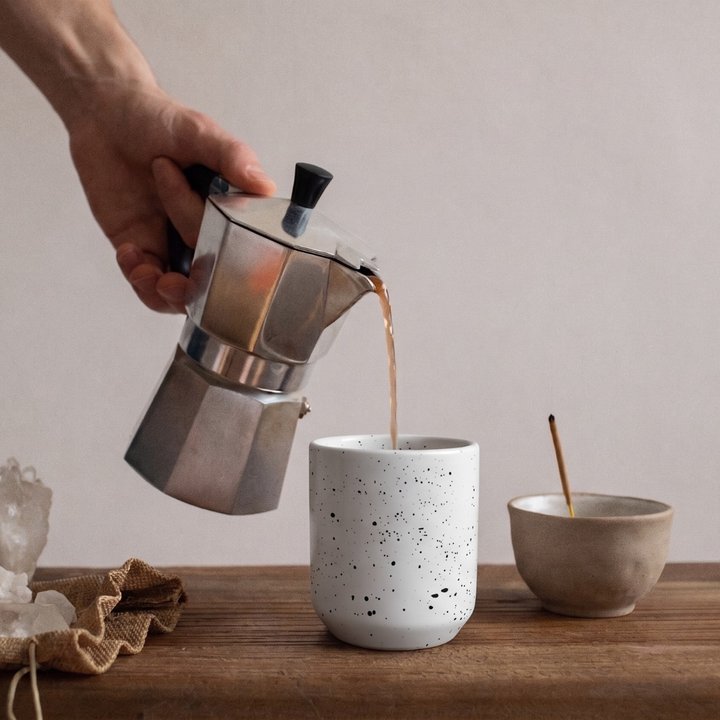 someone pouring coffee into ceramic cup 